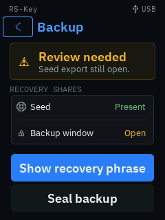 The trusted display’s Backup screen: an amber “Review needed — Seed export still open.” card above rows reading Seed: Present and Backup window: Open, with Show recovery phrase and Seal backup buttons